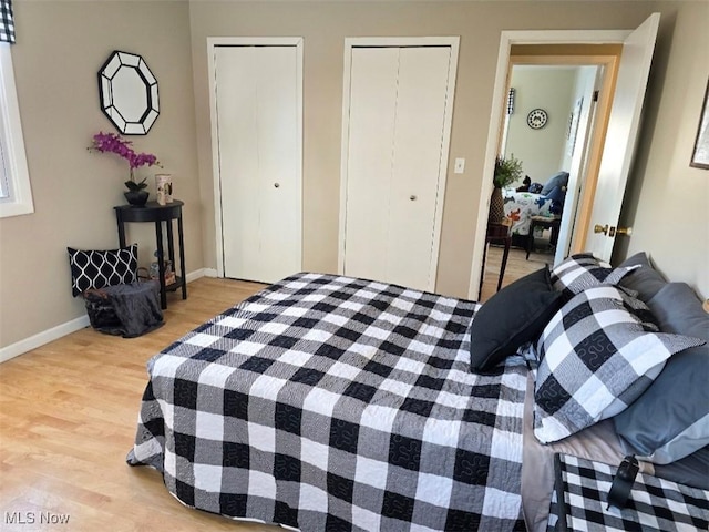 bedroom with light hardwood / wood-style flooring and two closets