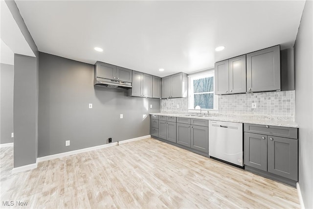 kitchen featuring dishwasher, sink, gray cabinetry, backsplash, and light wood-type flooring