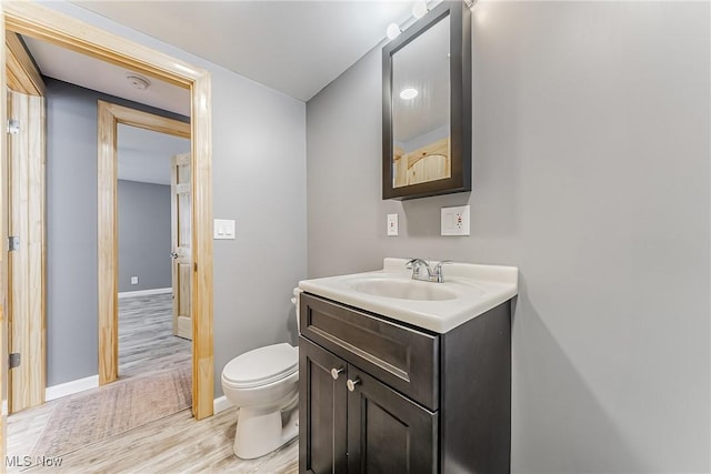 bathroom with hardwood / wood-style flooring, vanity, and toilet