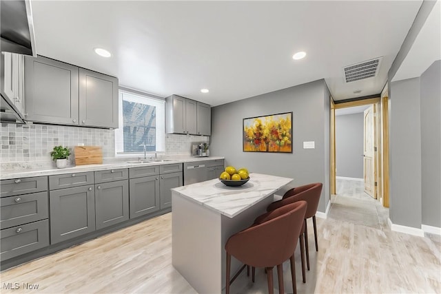 kitchen with gray cabinets, a center island, sink, and a kitchen breakfast bar