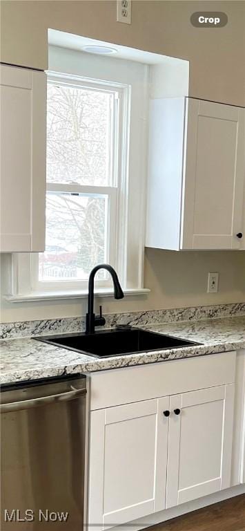 kitchen featuring white cabinetry, stainless steel dishwasher, and light stone counters