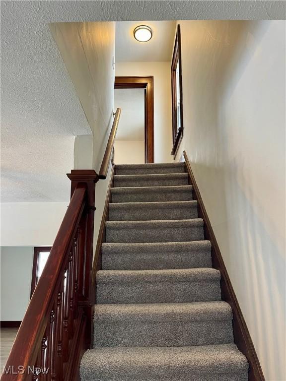 stairway featuring a textured ceiling