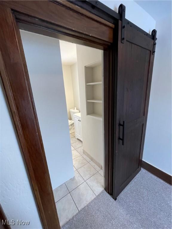 corridor with a barn door, built in features, and light tile patterned flooring