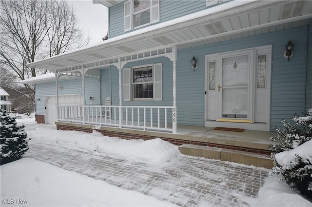 snow covered property entrance with a garage