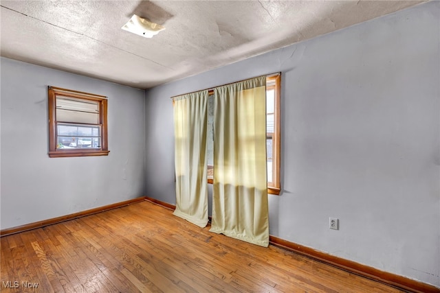 spare room with a textured ceiling and light wood-type flooring