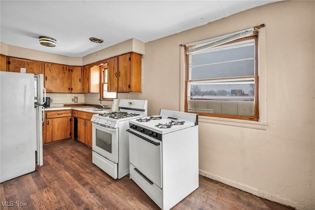 kitchen with dark wood-type flooring, white appliances, sink, and tasteful backsplash