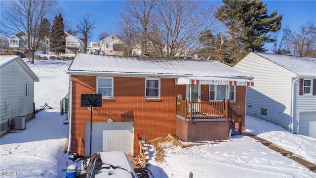 snow covered back of property featuring a garage