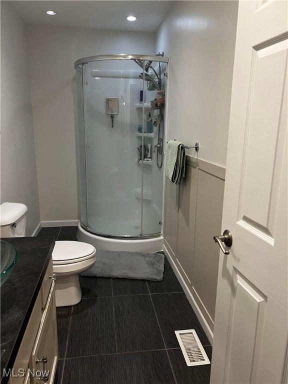 bathroom with toilet, an enclosed shower, and vanity