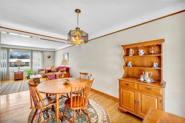 dining room featuring ornamental molding, a chandelier, and light hardwood / wood-style flooring