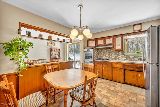 kitchen with a notable chandelier, stainless steel appliances, tasteful backsplash, and decorative light fixtures