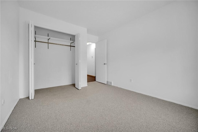 unfurnished bedroom with a closet and light colored carpet