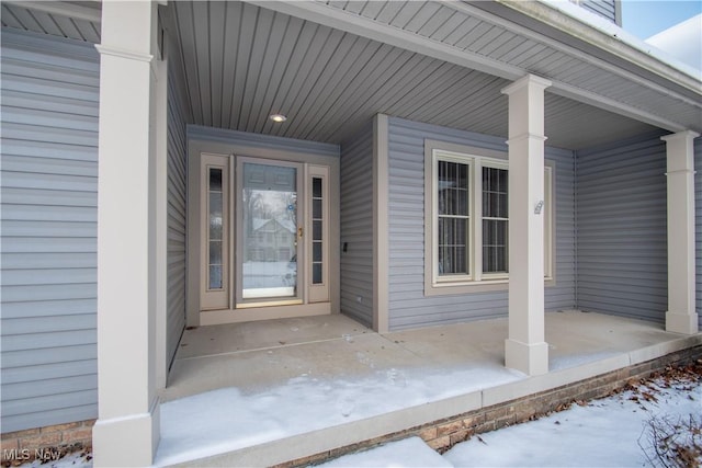 snow covered property entrance with covered porch