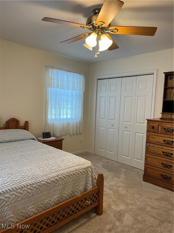 bedroom with ceiling fan, light colored carpet, and a closet