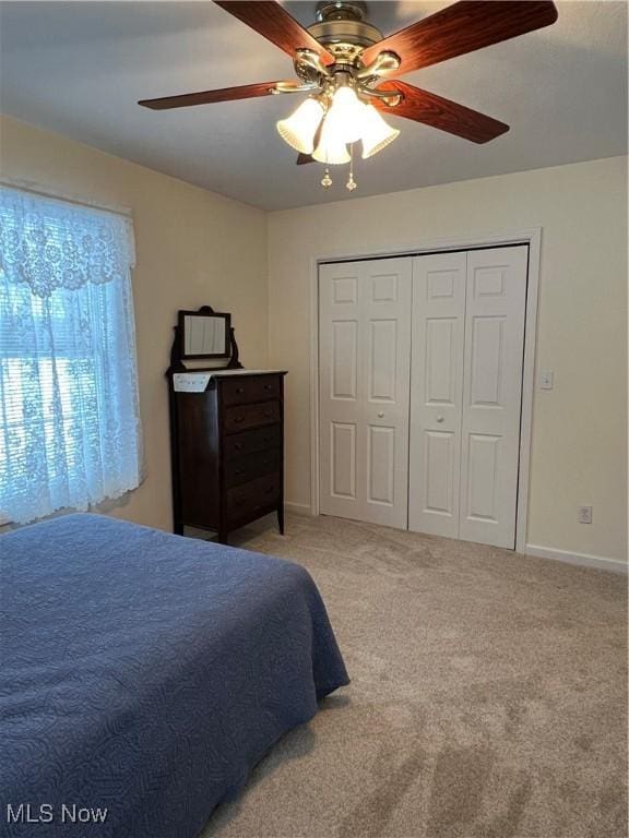 carpeted bedroom featuring ceiling fan and a closet