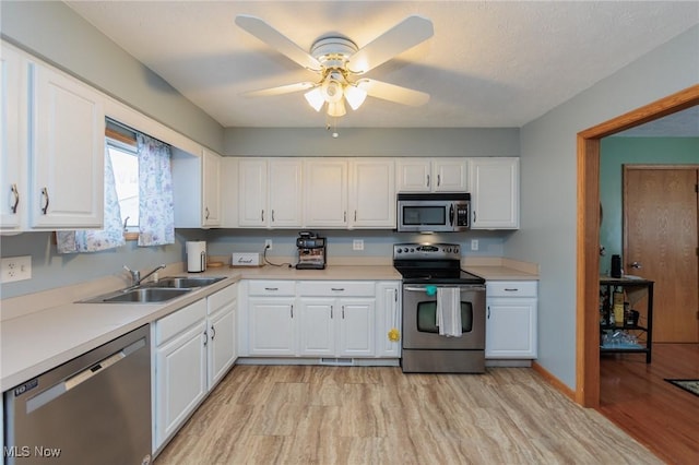 kitchen with ceiling fan, light hardwood / wood-style floors, sink, appliances with stainless steel finishes, and white cabinets