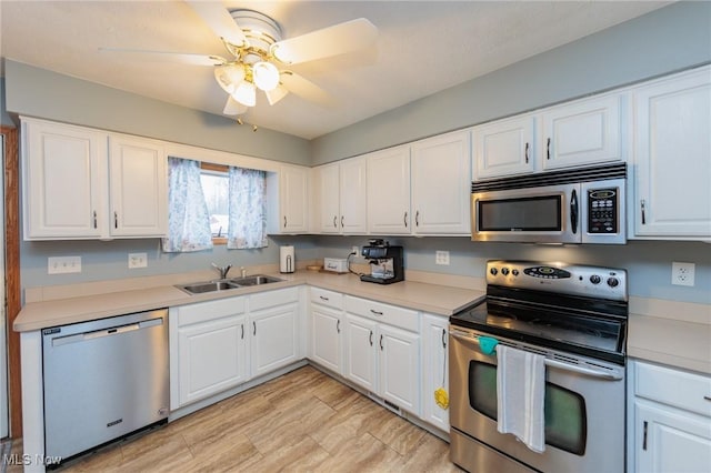 kitchen with ceiling fan, white cabinets, appliances with stainless steel finishes, and sink