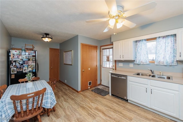 kitchen featuring stainless steel dishwasher, sink, white cabinetry, and black fridge