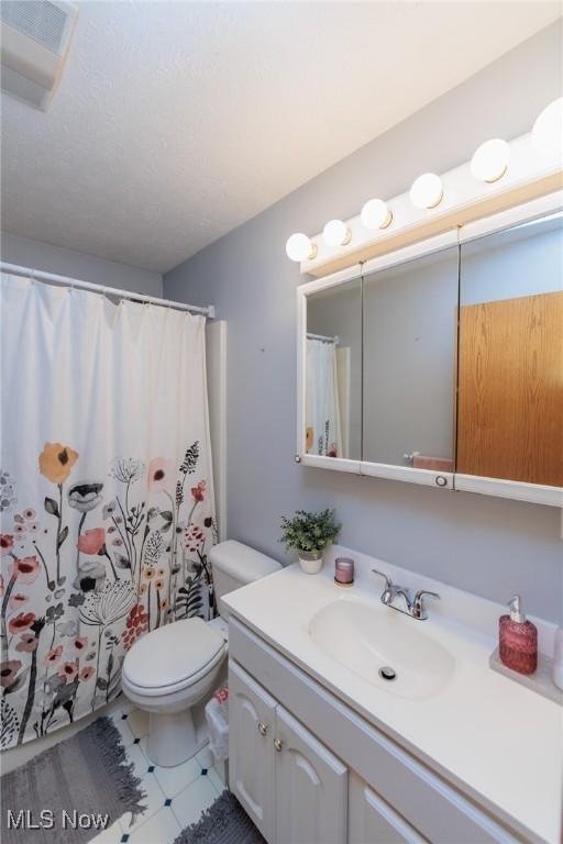 bathroom with toilet, vanity, and curtained shower