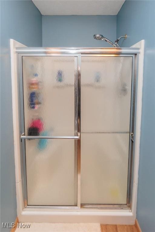 bathroom with an enclosed shower and hardwood / wood-style floors