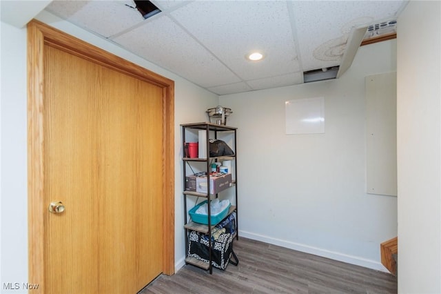 interior space with a drop ceiling and hardwood / wood-style floors