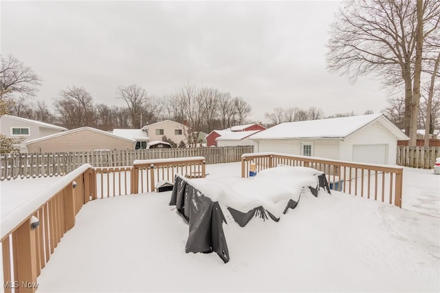 snow covered deck with a garage and an outdoor structure