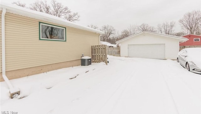 snow covered property with a garage and an outdoor structure