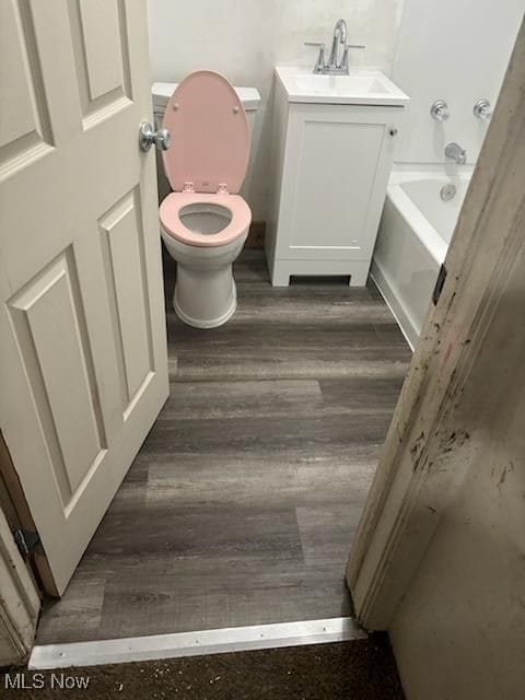 bathroom featuring toilet, a bathtub, wood-type flooring, and vanity