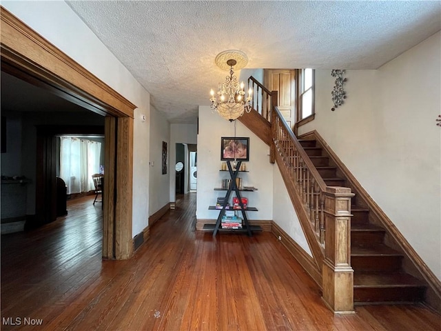 stairway with hardwood / wood-style floors, a notable chandelier, and a textured ceiling