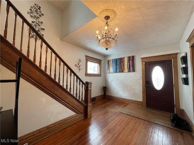 foyer featuring wood-type flooring, an inviting chandelier, and a textured ceiling