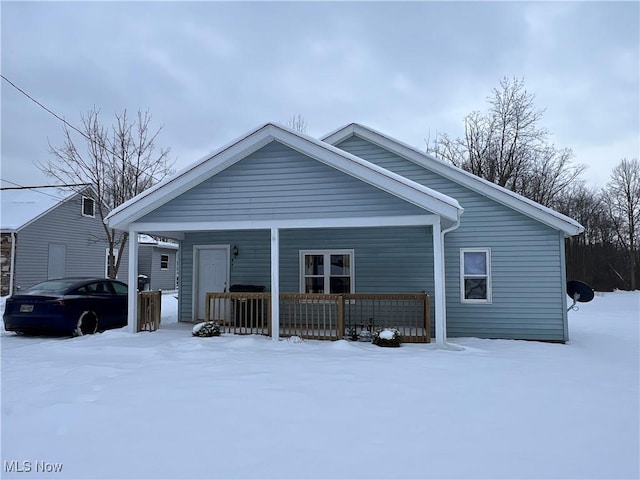 snow covered back of property featuring a porch