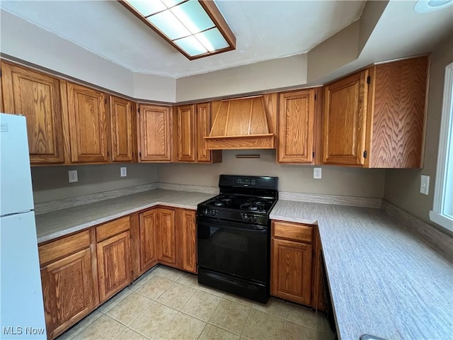 kitchen with custom exhaust hood, light tile patterned floors, black gas stove, and white refrigerator