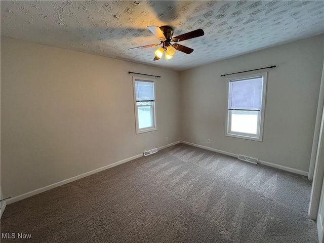 carpeted spare room featuring ceiling fan and a textured ceiling