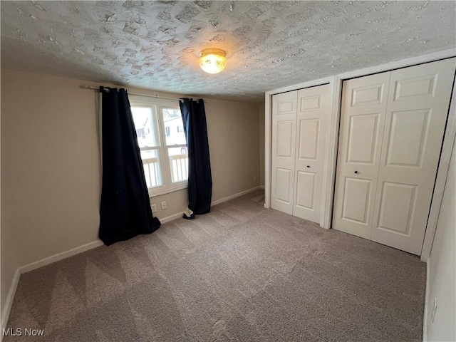 unfurnished bedroom with two closets, a textured ceiling, and carpet flooring