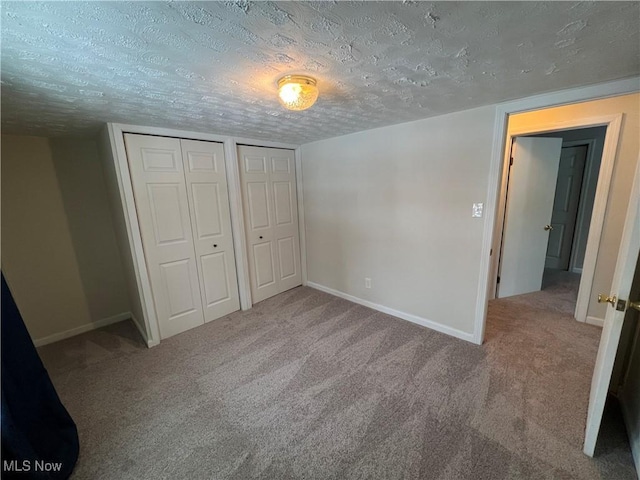 unfurnished bedroom featuring multiple closets, a textured ceiling, and carpet flooring