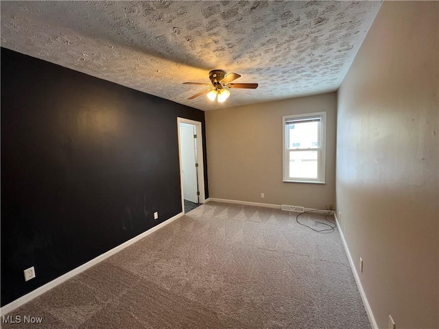 empty room featuring ceiling fan, a textured ceiling, and light carpet