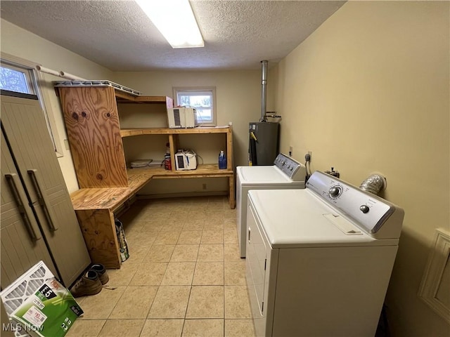 laundry area with a textured ceiling, light tile patterned floors, water heater, and washing machine and clothes dryer