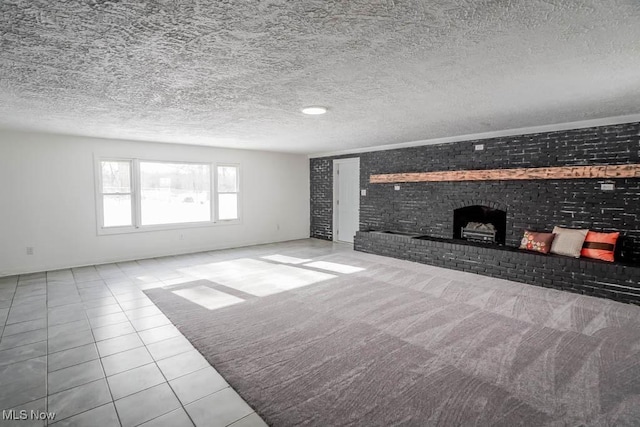 unfurnished living room featuring tile patterned flooring, a brick fireplace, brick wall, and a textured ceiling