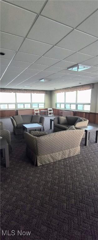 carpeted living room featuring a drop ceiling