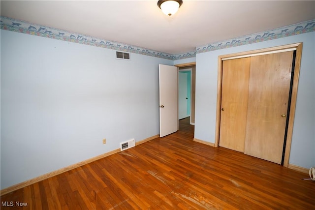 unfurnished bedroom with a closet and hardwood / wood-style floors