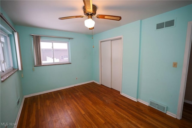 unfurnished bedroom with dark wood-type flooring, ceiling fan, and a closet