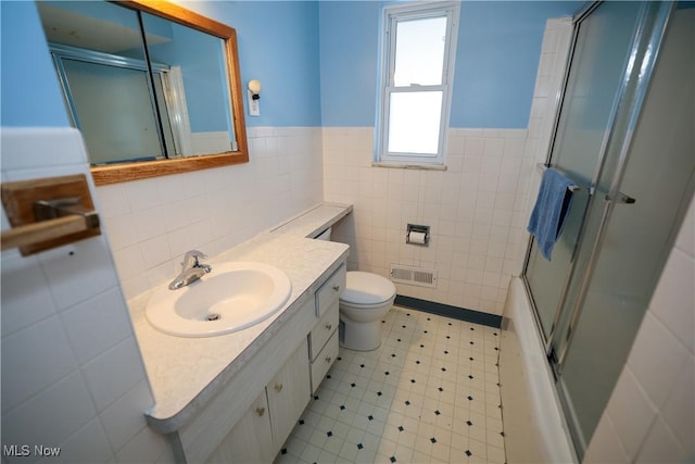 full bathroom with toilet, tile walls, vanity, and shower / bath combination with glass door