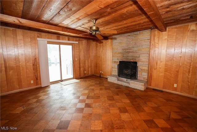 unfurnished living room with ceiling fan, wood ceiling, beamed ceiling, and wood walls