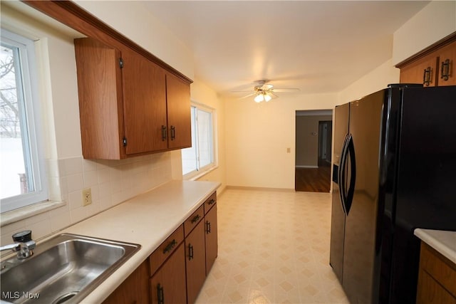 kitchen featuring ceiling fan, backsplash, sink, and black fridge