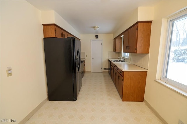 kitchen featuring sink, a wealth of natural light, black fridge, and tasteful backsplash