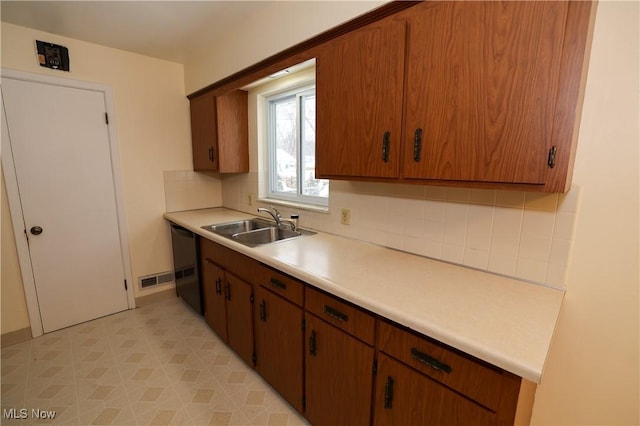 kitchen featuring decorative backsplash, sink, and black dishwasher