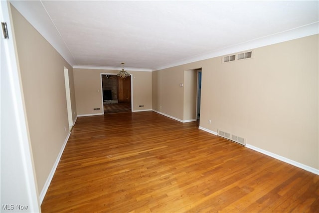 unfurnished room with a brick fireplace, hardwood / wood-style flooring, and crown molding