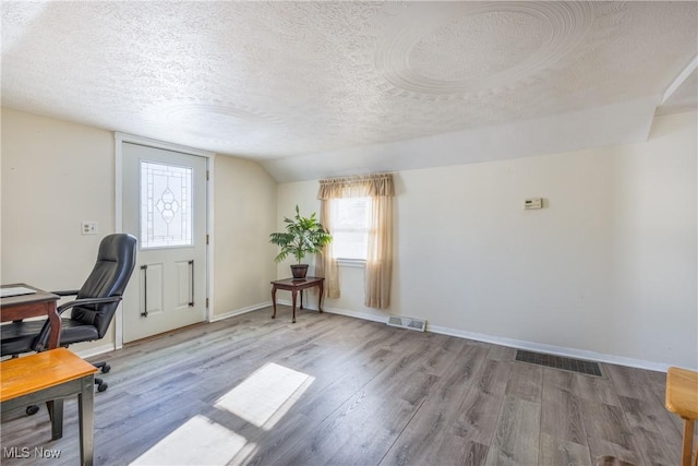 unfurnished office featuring vaulted ceiling, a textured ceiling, and hardwood / wood-style flooring