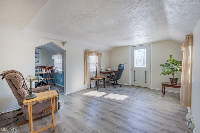 interior space with a textured ceiling, lofted ceiling, and light wood-type flooring