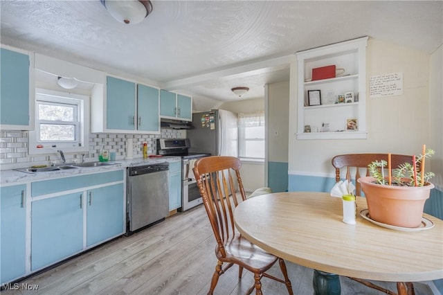 kitchen with backsplash, sink, light wood-type flooring, stainless steel appliances, and blue cabinets