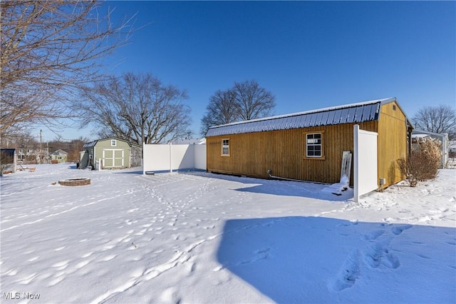 snow covered property with a storage unit and a fire pit